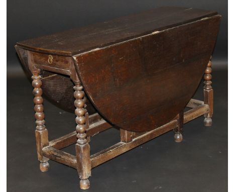 An 18th Century style oak oval drop leaf gate leg dining table, the plank top above a single end drawer on bobbin turned supp