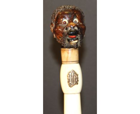 A 19th Century ivory page turner, the stained ivory finial as a Blackamoor with lever operated tongue and glass eyes, the ivo