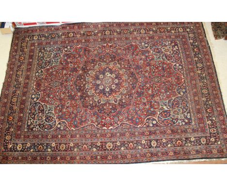 A Persian carpet, the central floral medallion in shades of blue, peach, cream and red, on a red floral decorated ground with