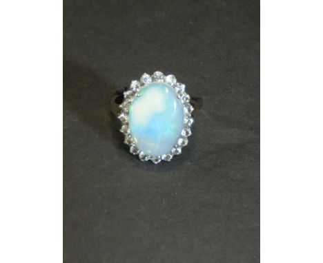 A dress ring, the central opal surrounded by simulated diamonds set on a yellow metal mount, size Q