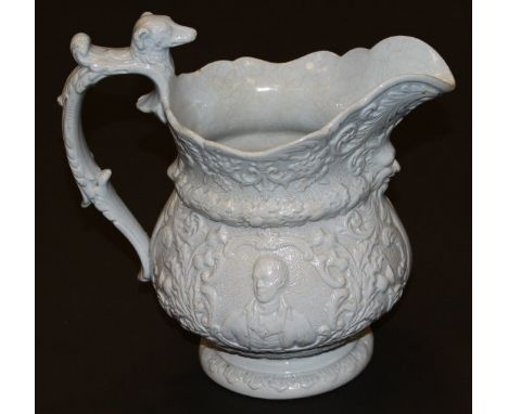 A 19th Century blue glazed relief moulded jug with mask head decoration and the handle with dog's head finial, the body relie