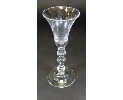 A mid 18th Century wine glass with waisted trumpet shaped bowl, the stem with a top knop, two inverted balusters and a base k