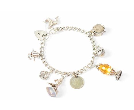 A silver charm bracelet with eight charms, to include a mermaid, an Isle of Man emblem, alarm clock, oil lamp, coin, 'Dusty B