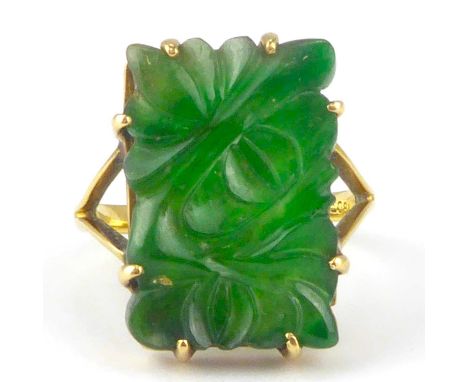 An 18ct gold ring with claw set carved floral green jade tablet, on split shoulders, size K, approx. 4g.