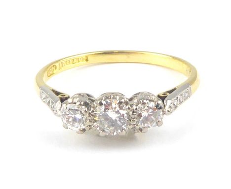 An 18ct gold three-stone diamond ring, with three platinum claw set brilliant cut diamonds, approx. 0.3ct, flanked by two at 