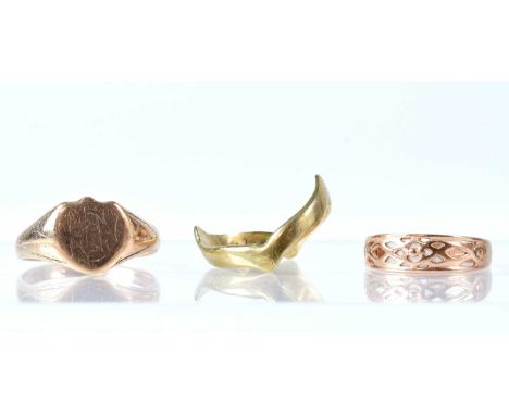 Three 9ct gold rings comprising a gentlemen's signet ring, size W, a wishbone ring, size U, and one with pierced decoration, 