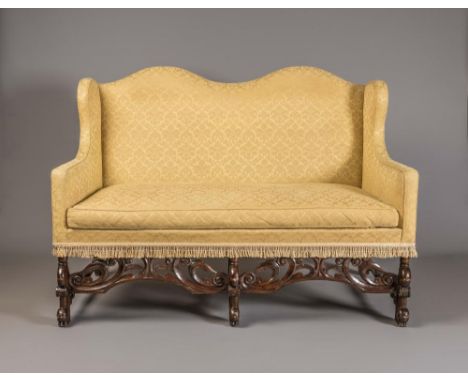 A WILLIAM AND MARY STYLE MAHOGANY CAMEL BACK SOFA, 20th century, upholstered in a yellow weave with tasselled frieze, waved t