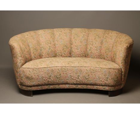 A FRENCH ART DECO BANANA STYLE SOFA, 1940's, upholstered in a floral tapestry, raised on stained beech block supports, 59 1/2