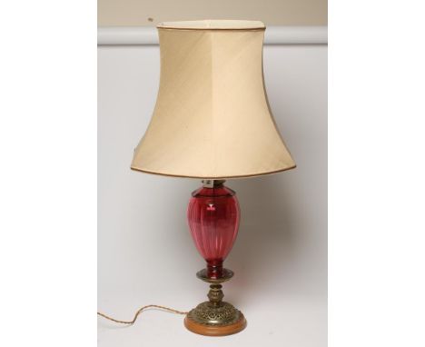 AN ELECTRIC TABLE LAMP BASE, the gilt brass fluted single fitting issuing from a panel cut cranberry glass ovoid body on a fo