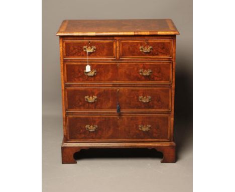 AN EARLY GEORGIAN STYLE WALNUT CHEST, the moulded edged quarter veneered and feather banded top over two short and three long
