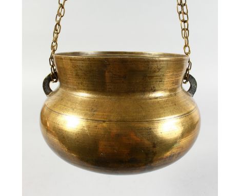 AN EARLY BRONZE CAULDRON with lugs and chain. 9ins diameter.