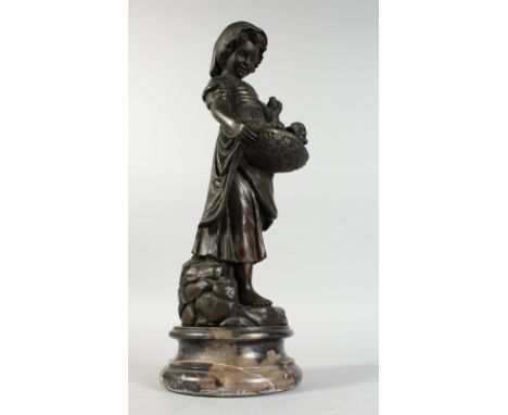 A BRONZE GROUP OF A YOUNG GIRL, carrying a basket of puppies, standing on a circular marble base. 23ins high.