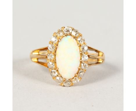 AN OPAL AND DIAMOND OVAL CLUSTER RING, with oval opal surrounded by sixteen diamonds.