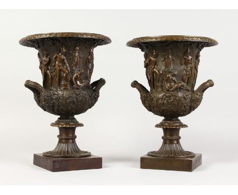 A GOOD PAIR OF BRONZE CLASSICAL TWO-HANDLED URNS on square bases. 12ins high.