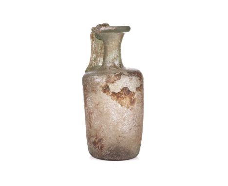 A Roman glass oil ewer of slightly perpendicular form with moulded strap handle to the everted rim, signs of oxidation to the