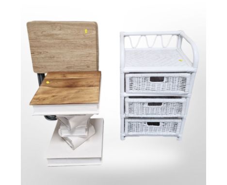 A painted wicker three drawer stand, two folding tables and a lamp table in the form of a stack of books 
