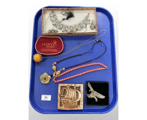 A group of costume jewellery to include jade pendant on cord chain, necklace with earrings, eagle brooch, signed pottery tile
