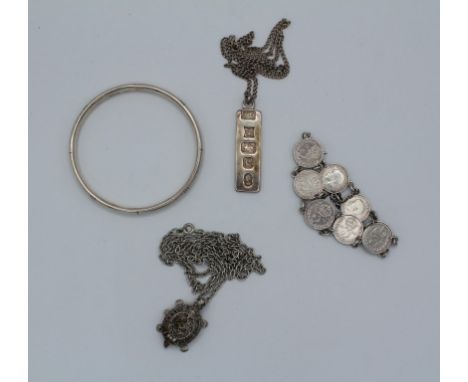 A group of silver jewellery comprising a silver jubilee ingot and chain, a sterling silver bangle, a pre 1920 coin bracelet a