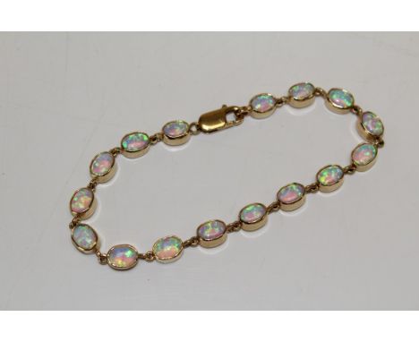 A 9ct yellow gold opal line bracelet, set with 16 cabochon opals, bezel set. Approximate length 20cms or 7.87 inches. Gross w