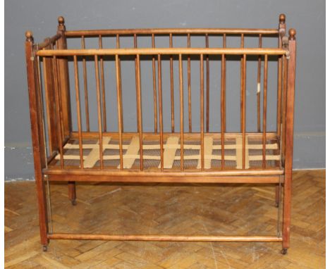 George Blake and Co, Oxford, an Edwardian beech collapsible cot/playpen with stick splats raised on stile supports with wood 