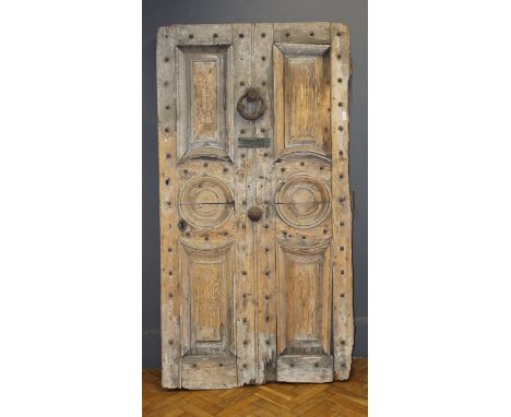 A large early 19th century pine panel door, having four fielded panels and a pair of roundel panels, mounted with a large iro