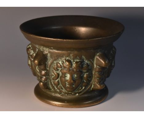 An Italian bronze mortar, flared bowl boldly cast in high relief with Medusa masks, lug handles, spreading circular base, 8cm