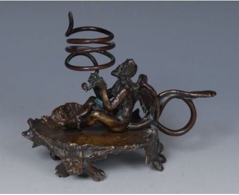 An early 19th century bronze chamberstick, the coiled sconce held aloft by the Devil, his tail curling into a handle, shaped 