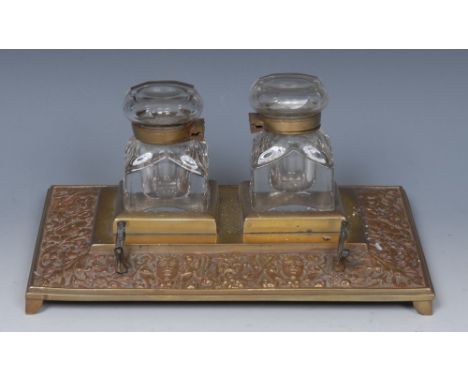 A Victorian brass rectangular inkstand, glass wells, the spreading base cast with a border of masks and foliage, bracket feet