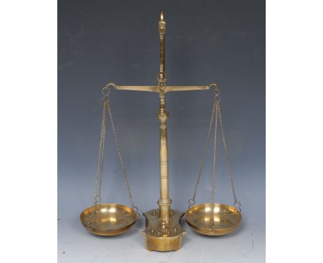 A set of early 20th century brass balance scales, probably pharmecutical, the shaped base with housing eight weights, 43cm hi