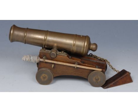 An early 20th century bronze desk top model signal cannon, oak carriage, wheel-chock attached by a chain, 15cm wide
