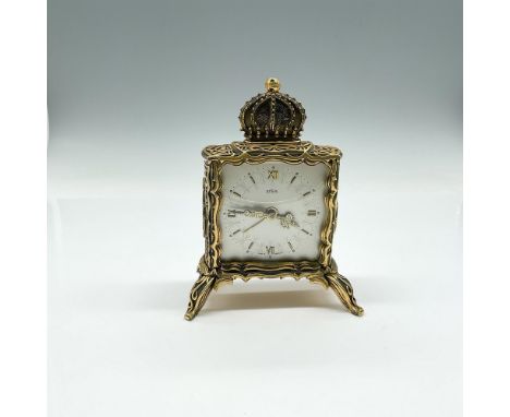 Gilt bronze footed case with engraved design and topped with crown. Clock face adorned with Roman numerals with alarm and tim
