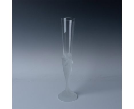 A clear glass with a frosted stem, featuring an intricate design of seven intertwined female faces with a flowing pattern lea