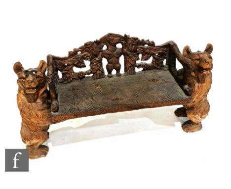 A contemporary Black Forest carved wooden bench seat, the reticulated back panel carved with a bear within fruiting vines, fu