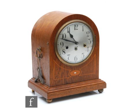 An Edwardian inlaid oak dome mantle clock, silvered dial with Arabic dial and striking Junghens movement, on stepped base and