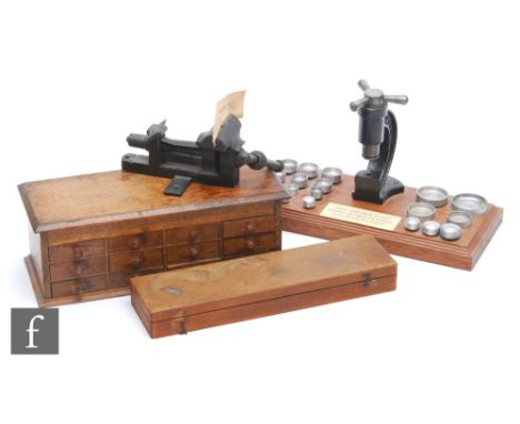 A watchmaker's tool or press used for replacing the glass in watch cases, mounted on a wooden base with accessories, width 32