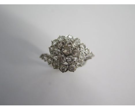 A large diamond set cocktail ring, the white shank and tapered shoulders to a high, wire under bezel - a central cluster encl