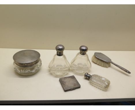 A pair of silver top scent bottles, a silver top tidy, a silver compact (mirror broken) and a brush and silver top glass flas