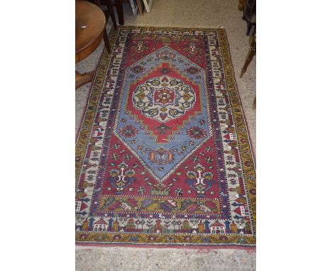 LARGE PATTERNED RUG WITH STYLISED DECORATION DEPICTING STREET SCENES SURROUNDING A CENTRAL PANEL, APPROX 225CM X 123CM