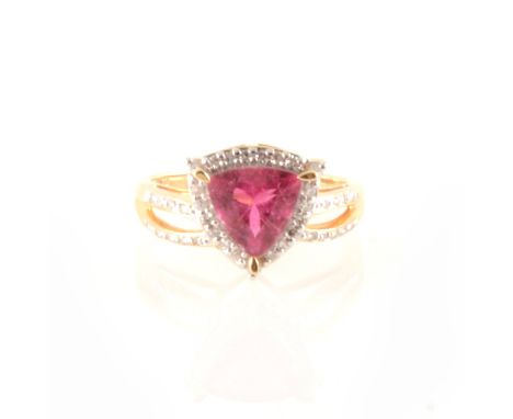 A rubelite and diamond ring, the triangular mixed cut rubelite 8.5mm diameter, three claw set, surrounded by twenty small rou