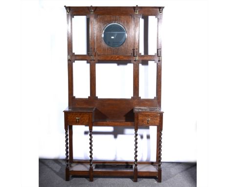 An oak hall stand, moulded cornice, panelled back with circular mirror, above two drawers and stick stand, barleytwist suppor