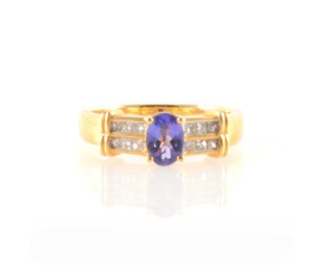 An oval tanzanite ring with diamond shoulders, the oval tanzanite 6.7mm x 4.7mm, four claw set in an 18 carat yellow mount wi