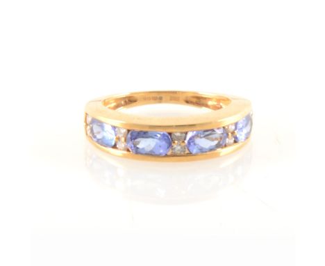 A tanzanite and diamond half eternity ring, the four oval mixed cut tanzanites 6mm x 3mm, channel set, separated by five pair