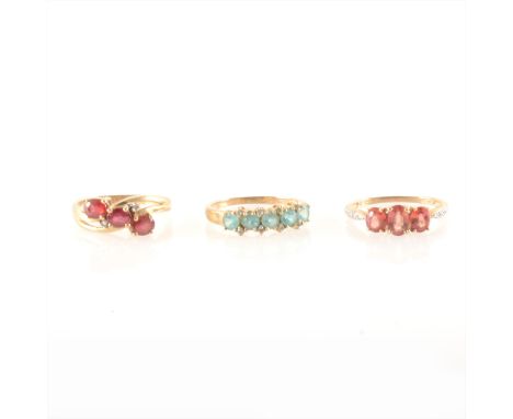 A red and white stone ring, the three red oval stones four claw set, with a small white stone set either side of the central 