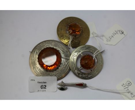 Three Scottish plated amber glass brooches and a silver miniature axe brooch