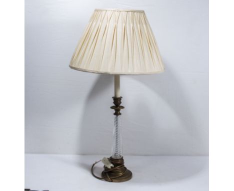 A glass and brass table lamp base with shade