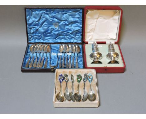 A cased set of twelve silver teaspoons and sugar tongs, a cased pair of silver pepperettes, and a set of six sterling and ena