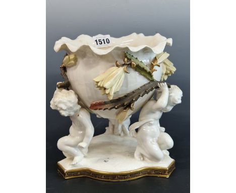 A MOORE BROTHERS LILY PAD PLANTER SUPPORTED BY THREE PUTTI.   H 20cms.