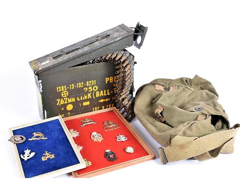 A 7.62mm Link (Ball-TR) ammunition case, complete with spent rounds on links, together with a small selection of cap badges, 