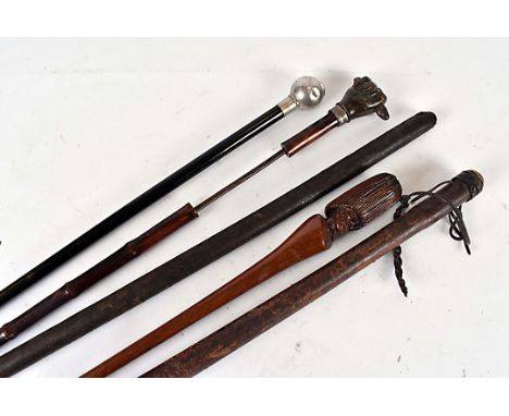 A horn handled sword stick, the terminal in the shape of a clenched fist holding something, together with a carved conductor'