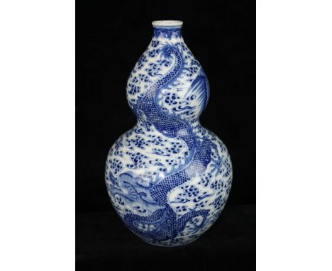 A Chinese blue and white porcelain double gourd vase, decorated with a large scaly dragon and a pheonix bird on a finely pain